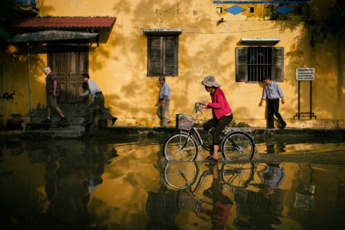 Woman riding bicycle through flooded area