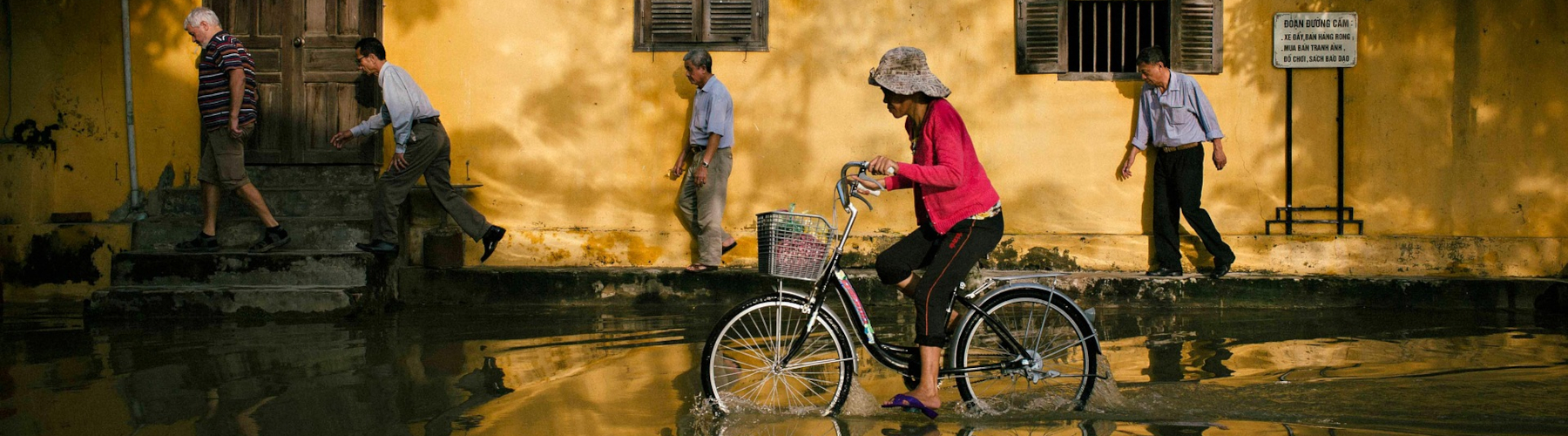 Woman riding bicycle through flooded area
